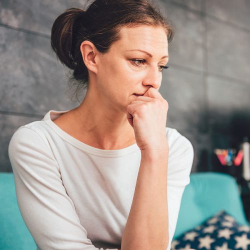 Sad woman sitting on a sofa in the living room